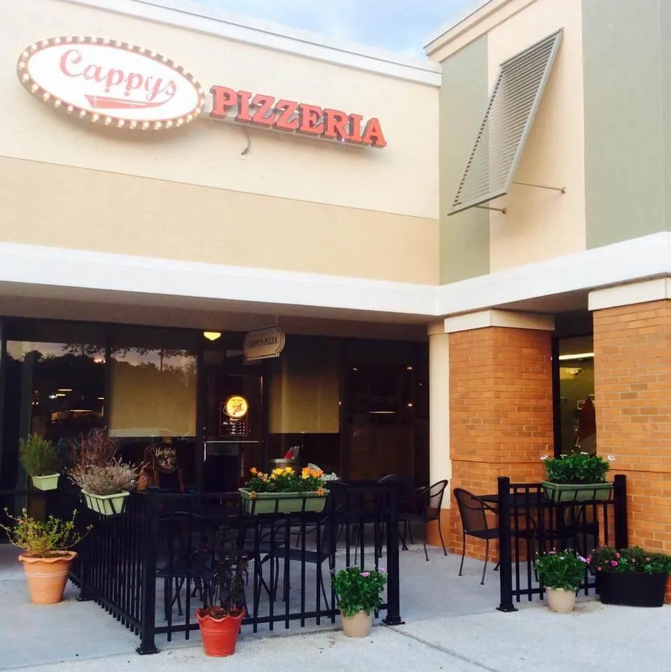 The Cappy's Pizzeria storefront in Tampa Palms, its lit marquee sign above the pet-friendly patio seating